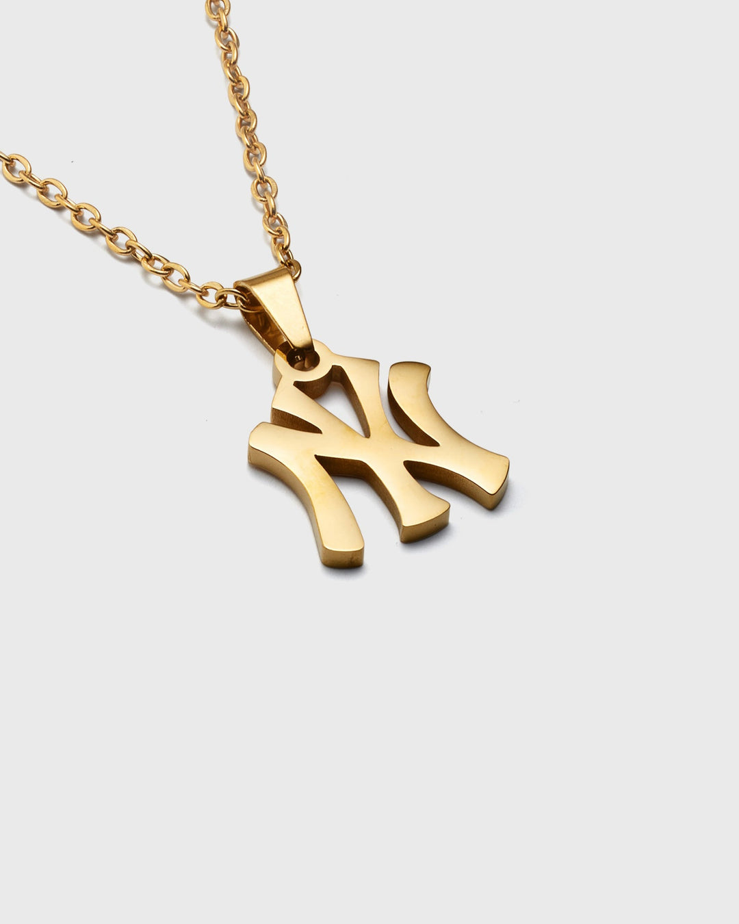 Gold necklace with a NY pendant on a white background